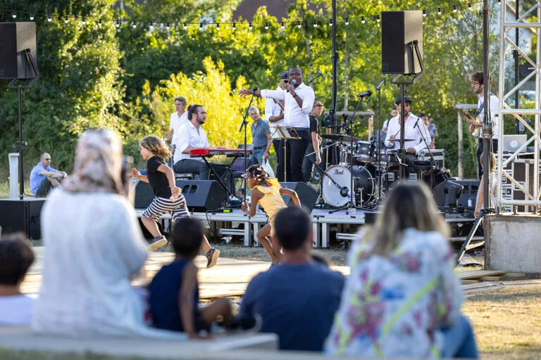 Fran's Orchestra, groupe de musiciens jouant en live lors d’un concert en plein air avec éclairages et ambiance festive.