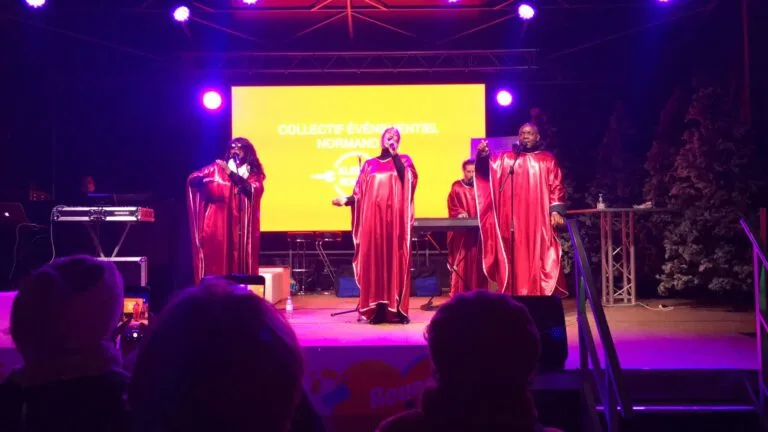 Amany, groupe de chanteurs gospel en robe rouge se produisant sur scène lors d’un événement en Normandie.
