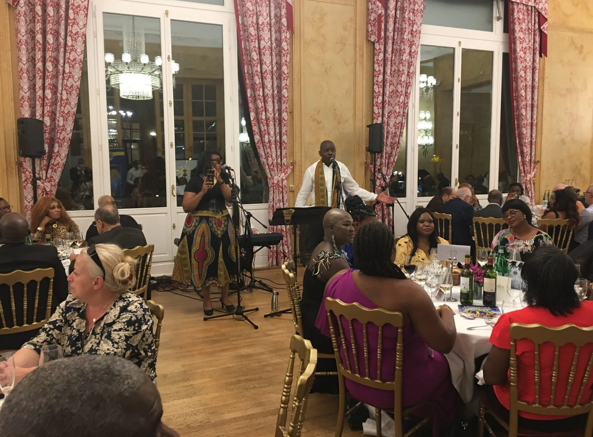 Jazz Pearl's, dîner de gala avec un orateur sur scène, accompagné d’une chanteuse et d’invités attablés dans une salle élégante ornée de lustres.