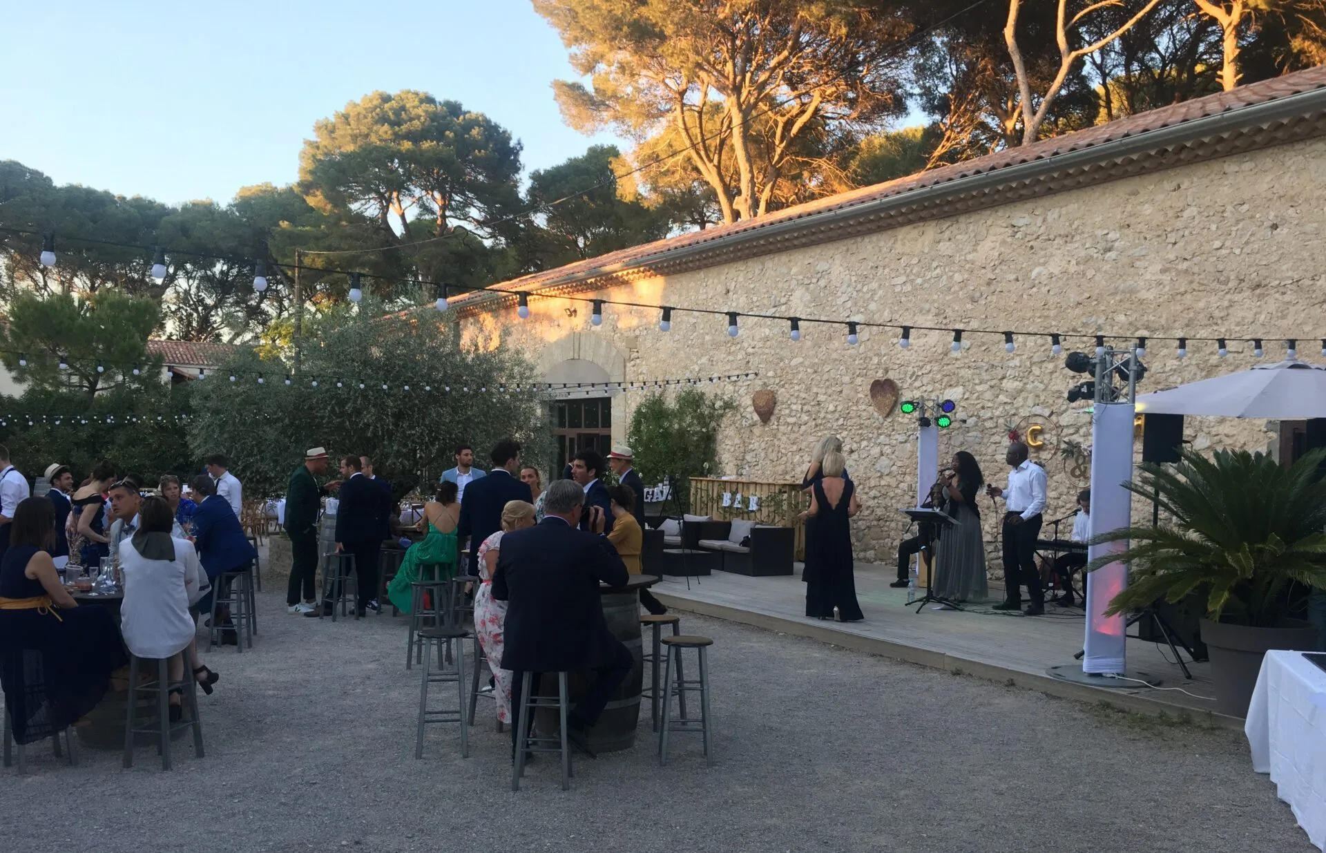 Jazz Pearl's, réception élégante en extérieur avec un concert live sur scène, des invités en tenue de soirée et une ambiance festive sous des lumières guinguette.