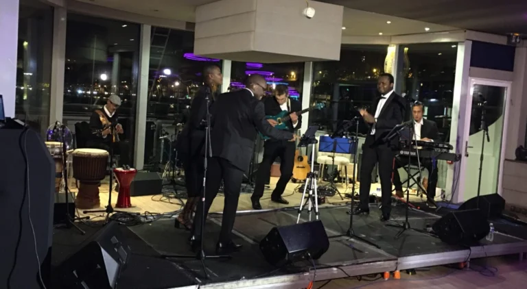 Fran's Orchestra, groupe de musiciens jouant en live sur une scène moderne avec éclairage violet lors d’un événement élégant en soirée.