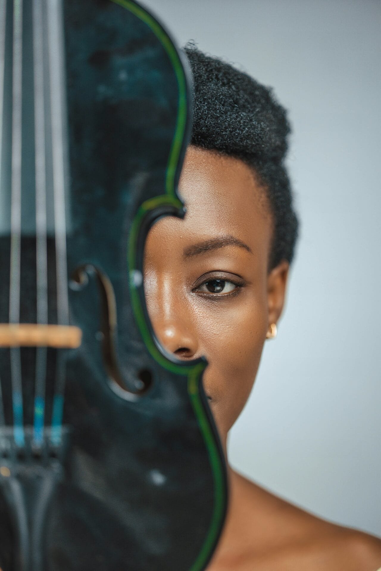 Portrait artistique d’une femme tenant un violon qui cache la moitié de son visage, illustrant le lien entre musique et identité.