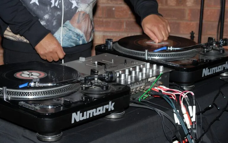 DJ mixant sur des platines vinyles Numark avec une table de mixage, en pleine performance.