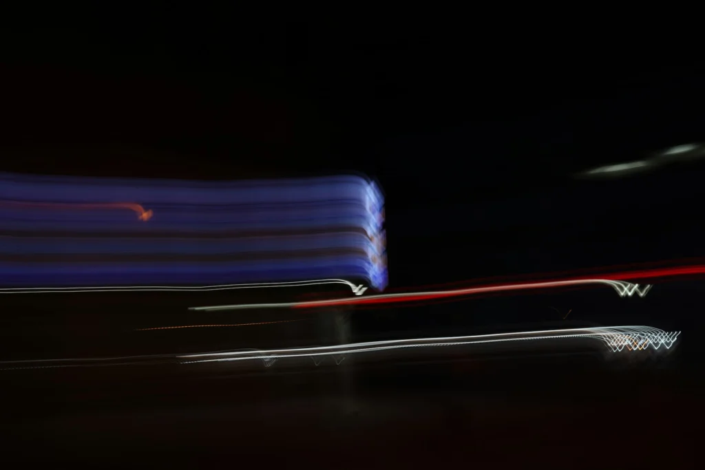 Traînées lumineuses floues et colorées sur fond noir, créées par un effet de pose longue en pleine nuit.