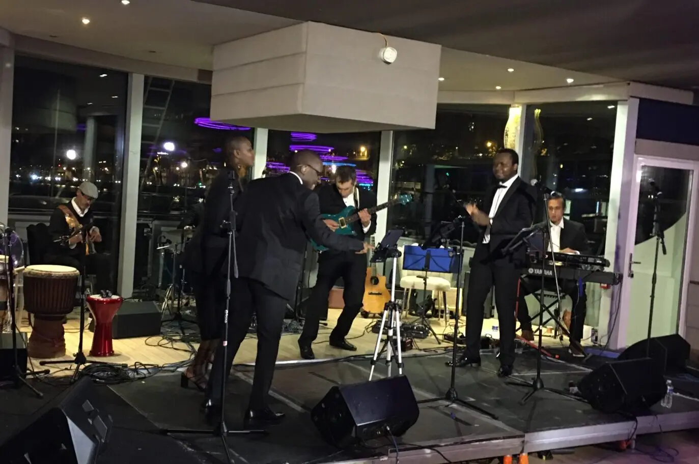 Groupe de musiciens et chanteurs en costume se produisant en live sur scène lors d’un événement en soirée.