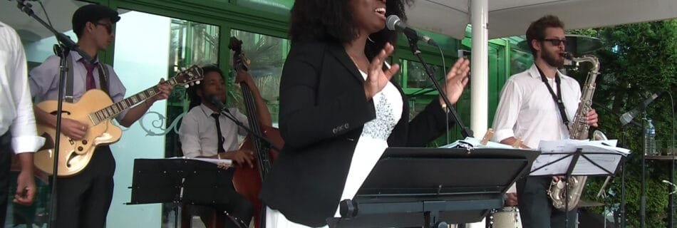 Groupe de musique live avec chanteuse, guitare, contrebasse, saxophone et batterie lors d’un événement en plein air.