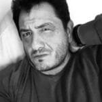 Portrait en noir et blanc d’un homme avec un regard intense, la main posée sur la nuque.