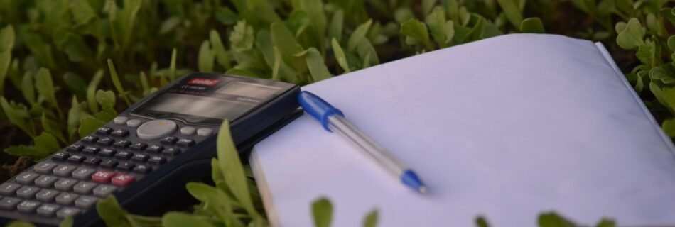 ne calculatrice, un stylo et un cahier posés sur de l’herbe, symbolisant l’étude en plein air.
